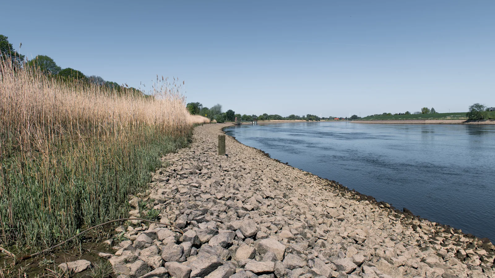 Fluss bei Niedrigwasser mit breit freiliegenden Kies- und Uferbänken